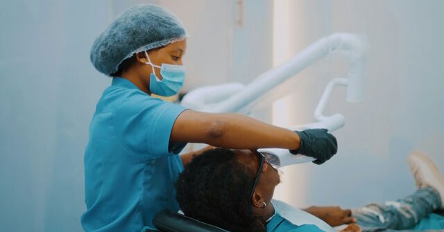 Profesional dental ajustando la lámpara sobre un paciente en el sillón