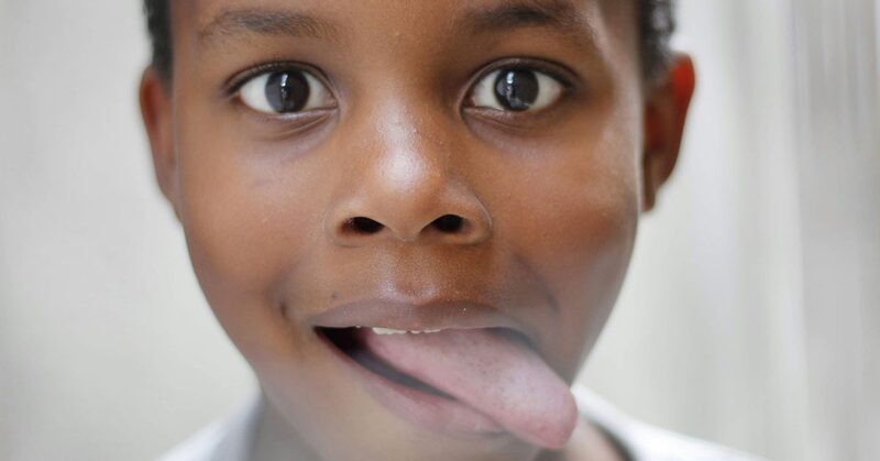 Niño sacando la lengua entre los dientes